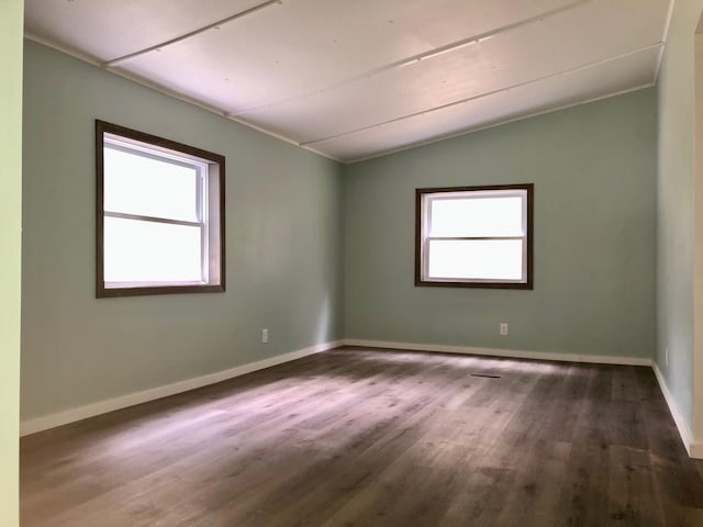 empty room with dark hardwood / wood-style floors, a healthy amount of sunlight, and vaulted ceiling