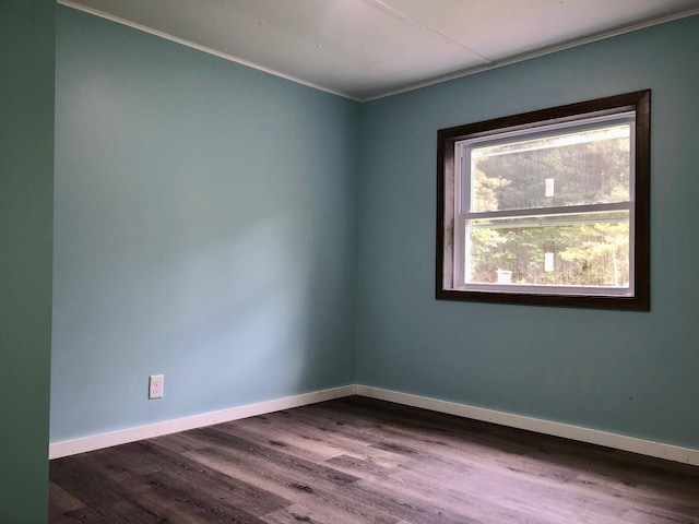 unfurnished room featuring dark wood-type flooring and ornamental molding