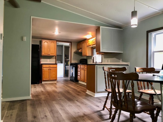 kitchen with decorative light fixtures, light hardwood / wood-style flooring, lofted ceiling, and black appliances