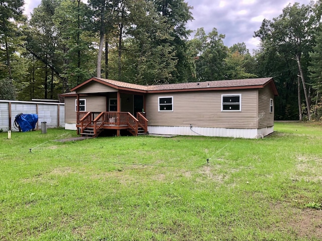 rear view of property featuring a lawn and a wooden deck