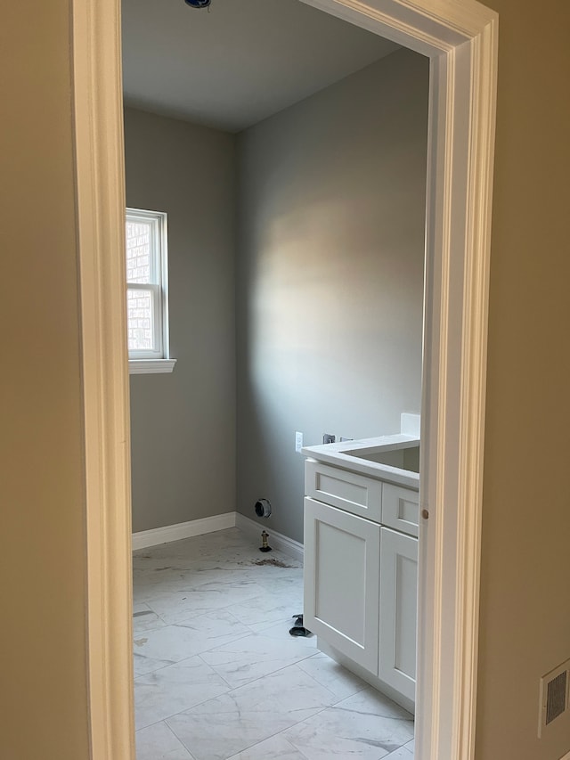 laundry area with visible vents, baseboards, and marble finish floor