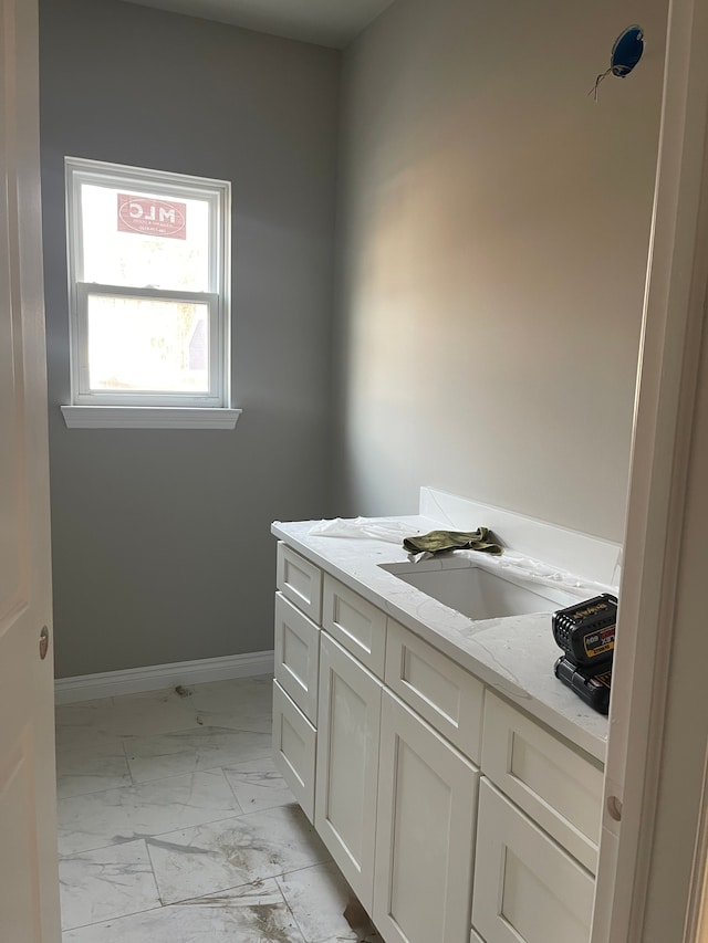 bathroom featuring baseboards, marble finish floor, and vanity