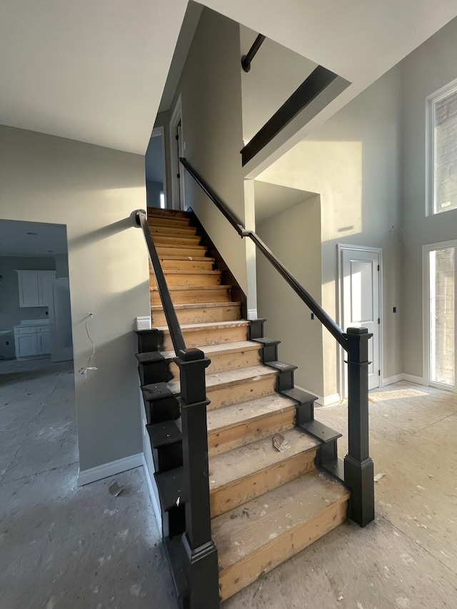 staircase with baseboards and a towering ceiling