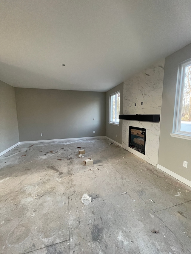 unfurnished living room with baseboards and a fireplace