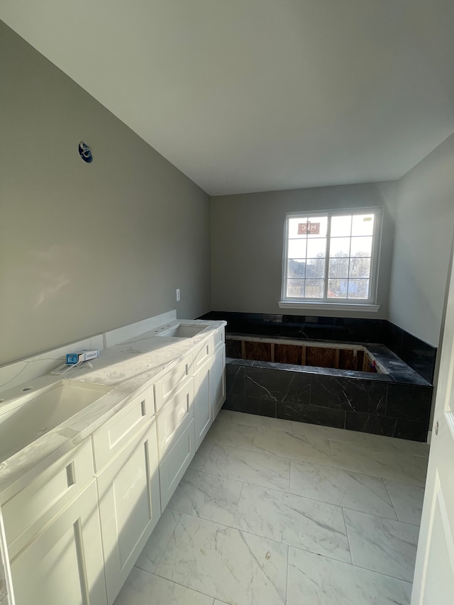 full bathroom with a bathtub, marble finish floor, and a sink