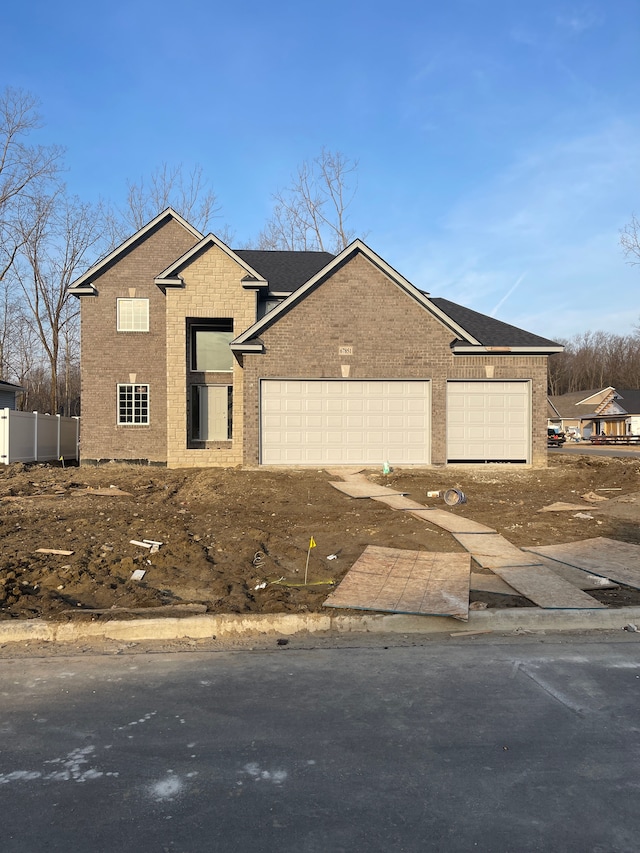 view of front of property featuring an attached garage, fence, brick siding, and dirt driveway