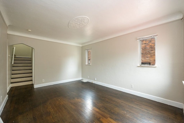 spare room with dark hardwood / wood-style flooring and crown molding