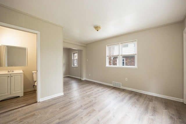 interior space featuring light wood-type flooring, crown molding, and sink