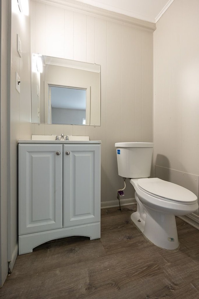 bathroom with hardwood / wood-style floors, vanity, toilet, and ornamental molding