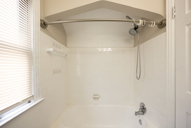 bathroom with tiled shower / bath combo and lofted ceiling