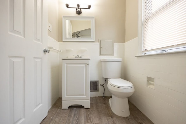 bathroom featuring hardwood / wood-style flooring, vanity, toilet, and tile walls