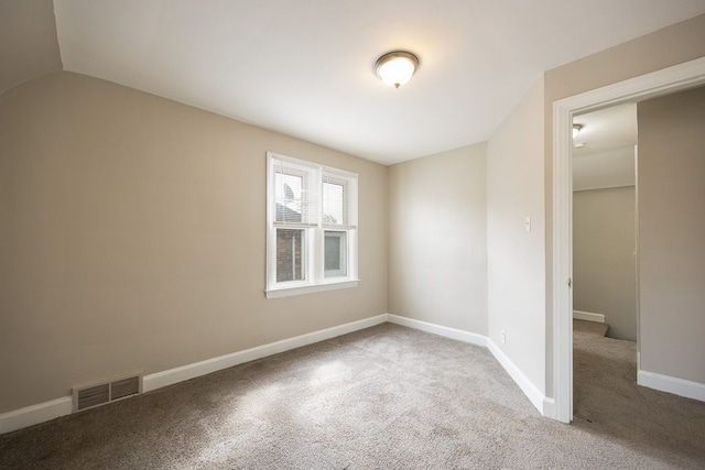 carpeted spare room with vaulted ceiling