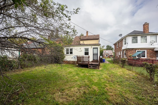 rear view of property featuring a yard and a wooden deck