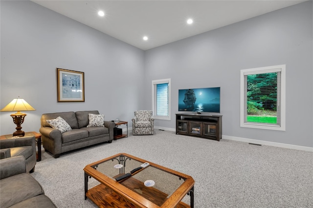 carpeted living room featuring a towering ceiling