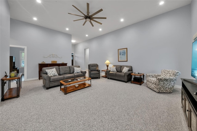 living room with a high ceiling, light colored carpet, and ceiling fan