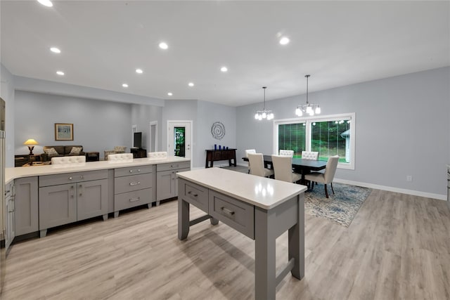 kitchen with a chandelier, light hardwood / wood-style floors, hanging light fixtures, and gray cabinetry