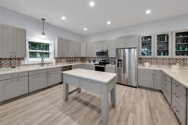 kitchen with pendant lighting, gray cabinetry, sink, decorative backsplash, and appliances with stainless steel finishes