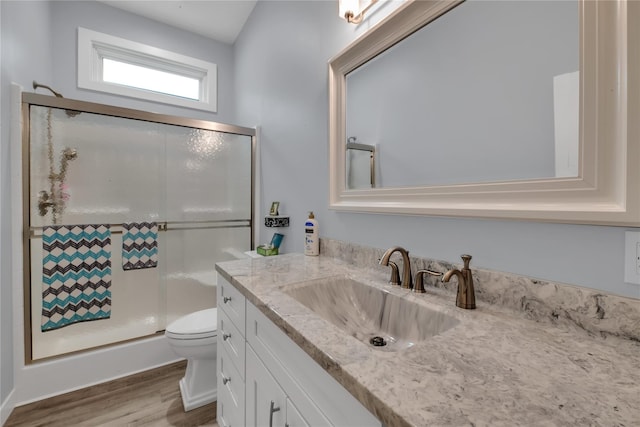 bathroom featuring wood-type flooring, vanity, toilet, and walk in shower