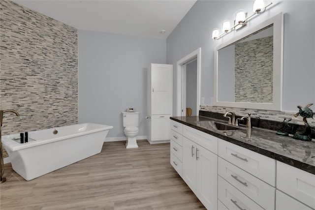 bathroom featuring vanity, hardwood / wood-style flooring, a washtub, decorative backsplash, and toilet