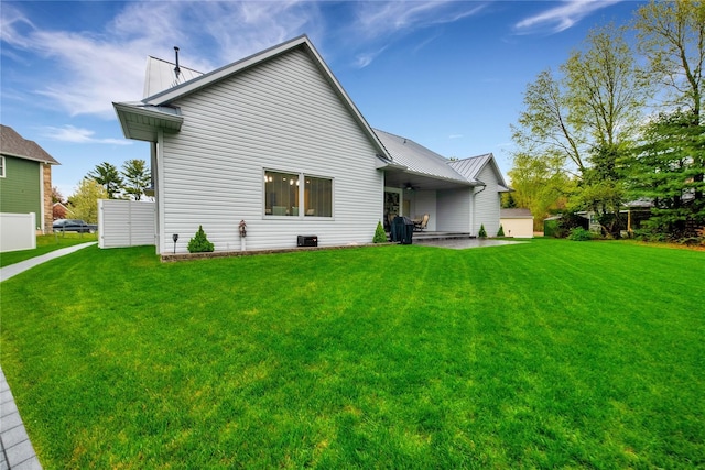 rear view of house with a patio, ceiling fan, and a lawn