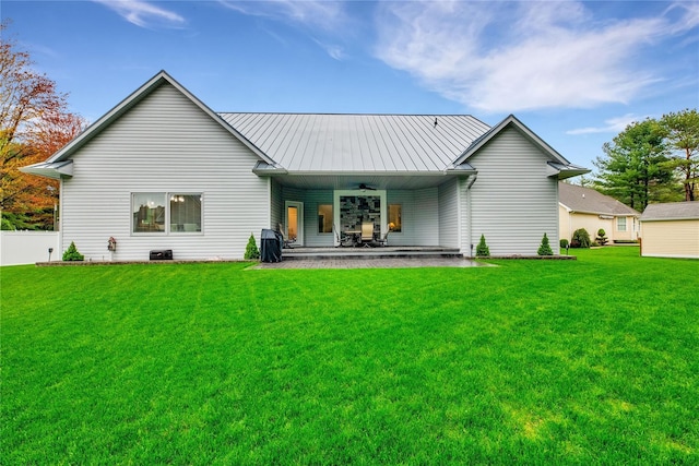 rear view of property featuring ceiling fan and a yard