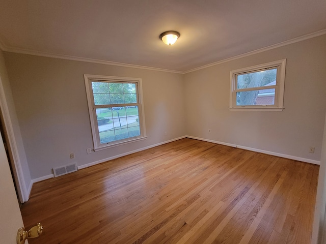 spare room with ornamental molding and light wood-type flooring