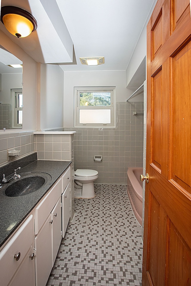 full bathroom with vanity, toilet, tile walls, and  shower combination