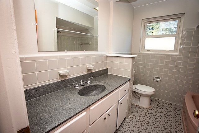 bathroom featuring a shower, vanity, tile walls, and toilet