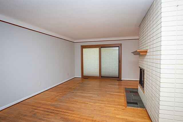 31990 Nottingwood St, Farmington Hills, MI 48334 - unfurnished living room featuring light wood-style flooring, a brick fireplace, and baseboards