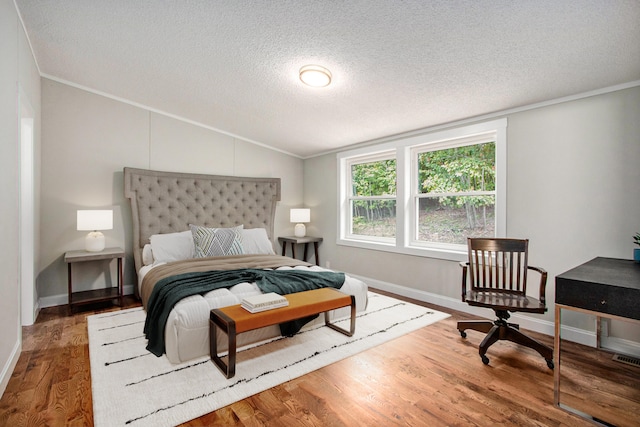 bedroom with a textured ceiling, crown molding, vaulted ceiling, and hardwood / wood-style flooring