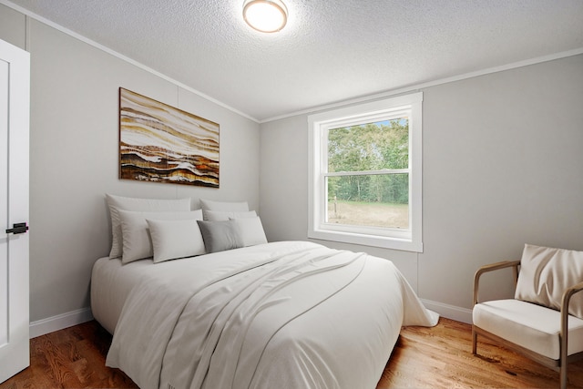 bedroom with wood-type flooring, a textured ceiling, and crown molding