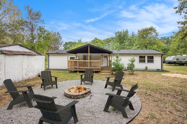 back of house with a fire pit, a wooden deck, and a lawn