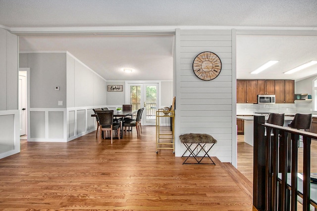 dining space with wood-type flooring, a textured ceiling, and ornamental molding