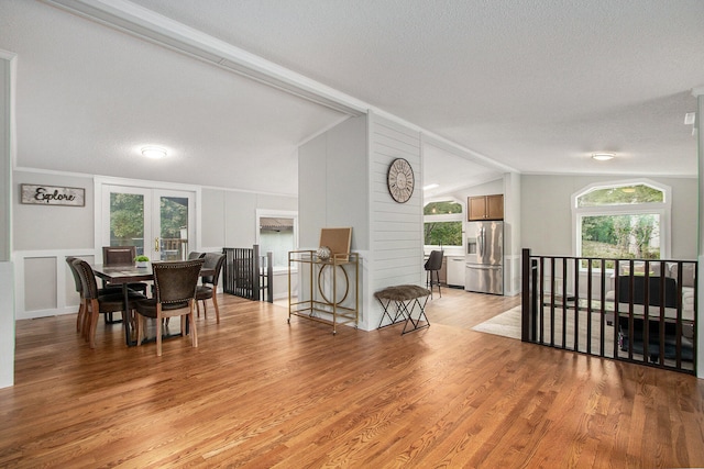 dining area with a textured ceiling, lofted ceiling, and light wood-type flooring