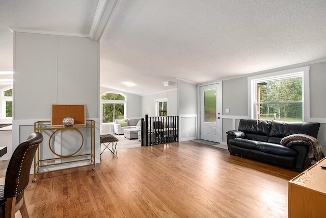 living room featuring vaulted ceiling, hardwood / wood-style floors, a textured ceiling, and ornamental molding