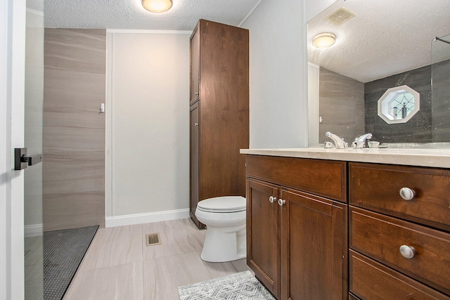 bathroom featuring vanity, tile patterned flooring, toilet, tiled shower, and a textured ceiling