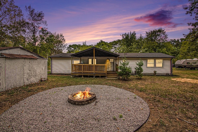 back house at dusk with a yard, an outdoor fire pit, and a wooden deck