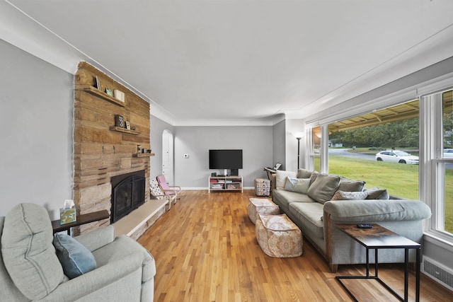 living room featuring a fireplace, light hardwood / wood-style floors, and ornamental molding