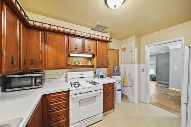 kitchen featuring decorative backsplash, water heater, light hardwood / wood-style floors, and white appliances