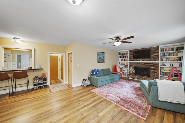 living room featuring ceiling fan, hardwood / wood-style floors, and a brick fireplace