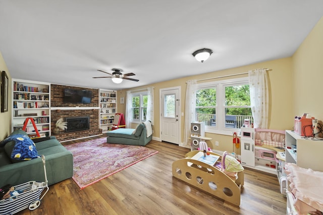 living room featuring a fireplace, wood-type flooring, ceiling fan, and built in shelves