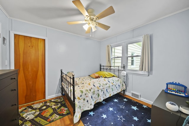 bedroom with dark wood-type flooring, ceiling fan, and ornamental molding