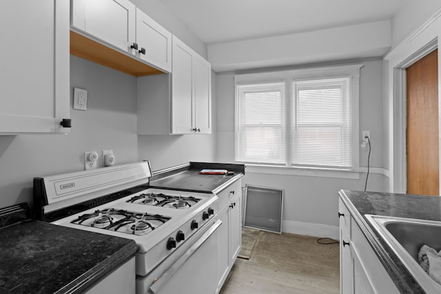 kitchen featuring sink, white cabinetry, white gas range oven, and light hardwood / wood-style flooring