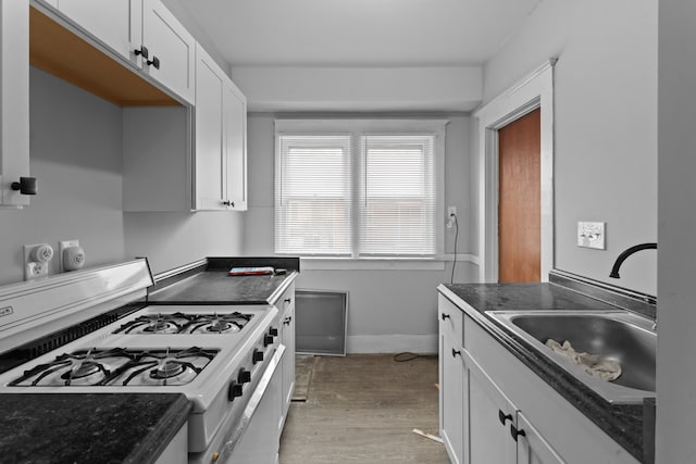 kitchen with light hardwood / wood-style floors, white cabinetry, gas range gas stove, and sink