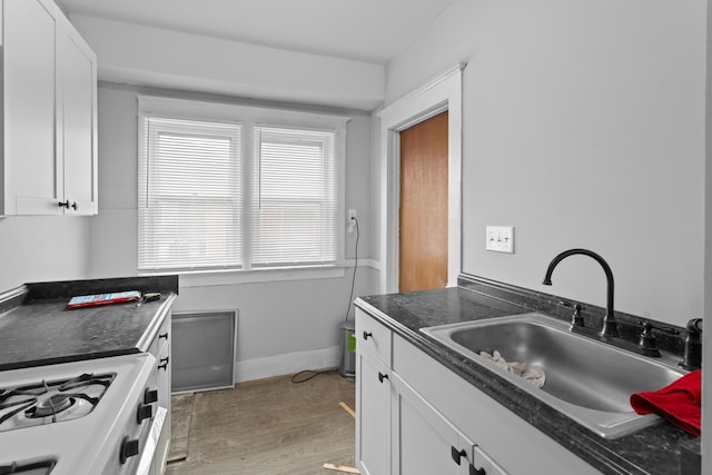 kitchen with white cabinets, white range, light wood-type flooring, and sink