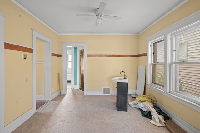 empty room featuring light carpet, crown molding, and a healthy amount of sunlight