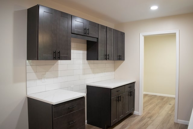 kitchen featuring dark brown cabinetry, light hardwood / wood-style floors, and tasteful backsplash