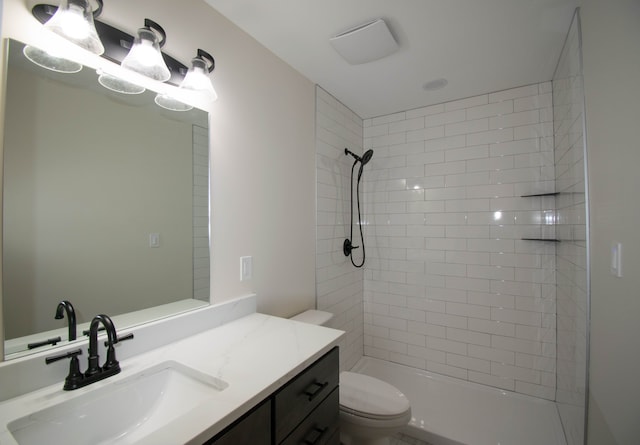 bathroom with tiled shower, vanity, and toilet