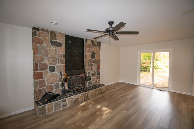 58085 Dulwich, Washington, MI 48094 - unfurnished living room with a wood stove, baseboards, ceiling fan, and wood finished floors