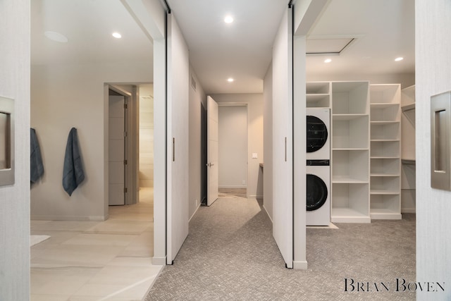 hallway with light colored carpet and stacked washer and dryer